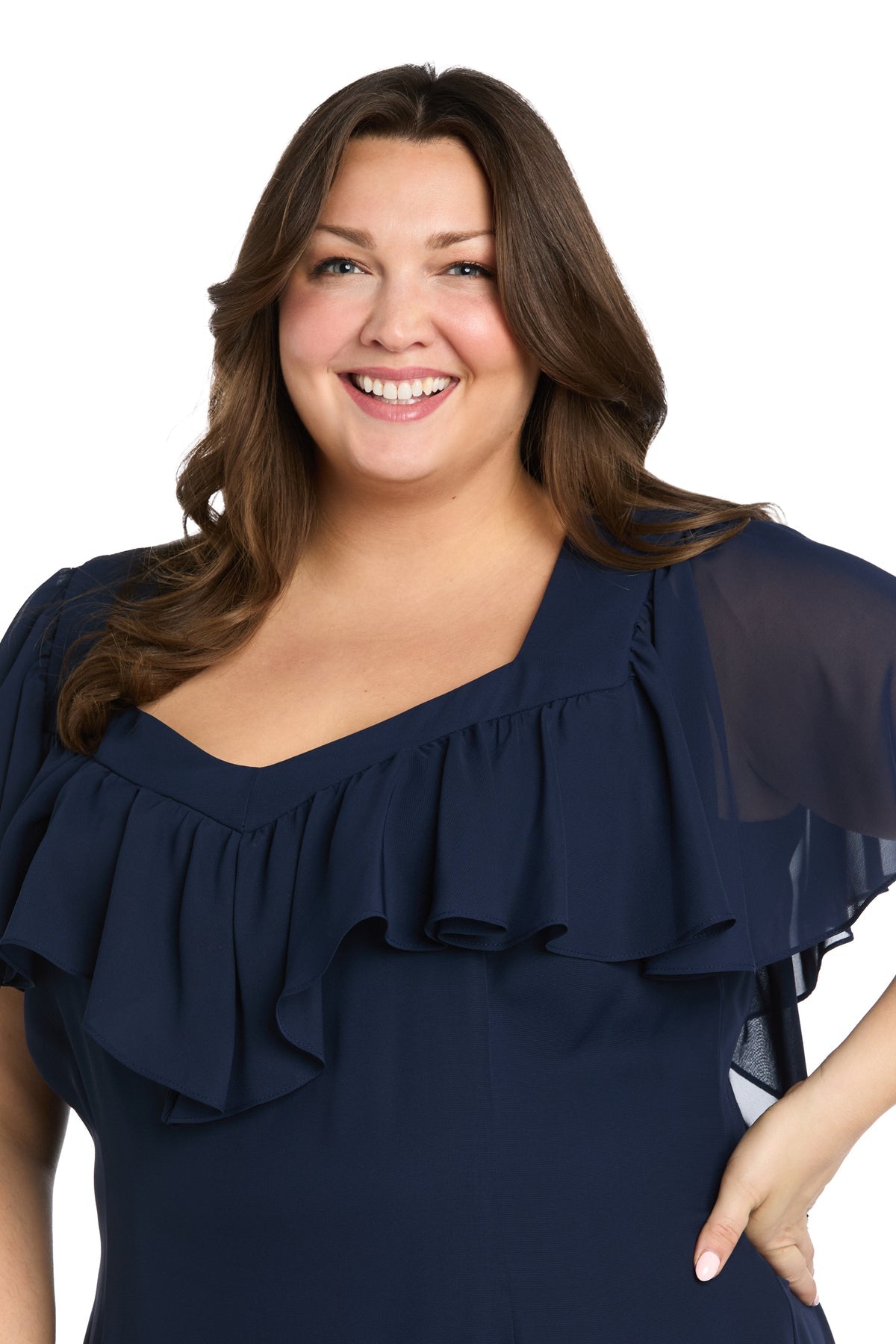 A woman with long brown hair smiles at the camera in the Plus-Size Navy Party Dress: R&M Richards 4054W, a knee-length ruffled design, against a white background.